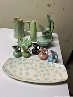 Ceramic assortment arranged together showing variety of vases, pitchers, dish and serving tray.
