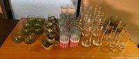 Wide view of vintage glasses including amber goblets, patterned mid-century style glasses, and clear beer and water glasses.