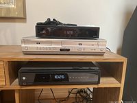Arris HD Dual Tuner DVR on top, Samsung DVD and VHS player in the middle, and Motorola DVR on the bottom shelf.