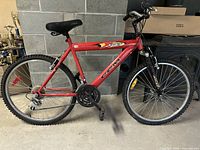 Side angle view of red CCM X-Volt 24-inch mountain bike with visible frame, tires, and components.