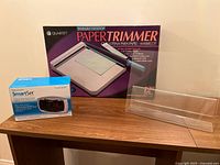 Photo showing original boxed Quartet paper trimmer and boxed Smart Set dual alarm clock on a shelf.