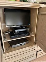 Photo of Toshiba flat-screen TV, Toshiba HiFi stereo, VHS player, Motorola digital box and DVR all housed in a wooden cabinet.
