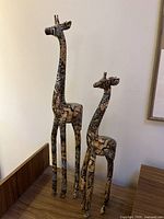 Full view of mother and child giraffe figurines displayed on wood surface, showing their height difference and design.