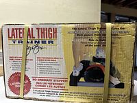 Front and side view of the box showing 'Lateral Thigh Trainer' branding and features including patented bi-directional pedal movement and targeted muscle toning benefits.