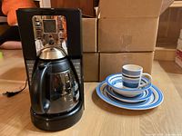Photo showing the Oster coffee pot and stacked blue and white striped Gibson dishes, including cups, bowls, lunch and dinner plates.