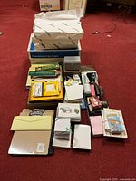 Wide view showing full lot contents including paper reams, stationery, and office tools spread out on floor