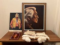 Overview showing framed portrait, framed photo, moccasins, and decorative item on table.