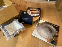 Boxed 3-piece blue serving dishes in bubble wrap and boxed round holiday platter.
