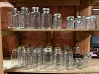 Multiple shelves of assorted clear glass sealer jars with metal lids, including Mason and Ball brands in varying sizes