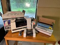 Wide shot showing both humidifier and vacuum sealer with their packaging on a wooden table in front of a window.