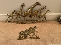 Overview of both brass giraffe key holders, larger with 6 giraffes and smaller with 3 giraffes, showing overall condition and relative sizes