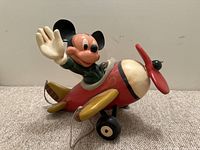 Three-quarter angle view of Mickey Mouse seated in red airplane