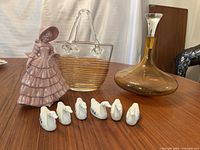 Image showing the full lot: Southern Belle figurine, clear and amber striped glass basket, amber decanter, and six white duck figurines.