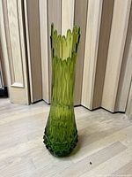 Full view of the tall green glass vase showing the scalloped swung top and faceted diamond texture body.