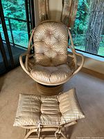 Swivel chair with foot rest in front, showing beige tufted cushion upholstery and rounded rattan base.