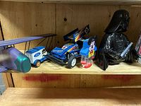 Shelf with Turbo Wing Buggy model car, Ford Model T toy, Mickey Mouse coin bank, and Darth Vader figure.