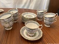 Set of nine Royal Albert Silver Birch teacups and saucers arranged on a wooden table showing full set and design details.