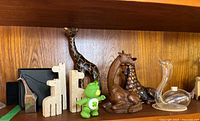 Full lot view showing wooden, glass, ceramic, and plastic collectible figurines including giraffes, swan, and Care Bear.