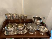 Full set laid out on wooden surface including goblets, creamer and sugar bowl, decorative container, trinket bowl, and water jug.