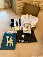 Photo showing white bathrobe, aromatherapy foot warming socks, cozy plush lounger, ankle booties, t-shirt, and Danier coat bag arranged on floor.