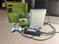 Xbox 360 Arcade console, one wired white controller, multiple games stacked, power brick, and original box.