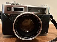 Front and front-left angled views showing Yashica Electro 35 camera body, Color-Yashinon DX 45mm f/1.7 lens, and part of attached strap and accessories.