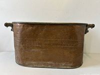 Front view of antique copper boiler showing wood handles, patina, and overall rectangular shape with rounded edges.