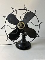 Front view of black metal 17-inch oscillating table fan with curved wire blade guard and four black blades. Central Westinghouse logo visible.