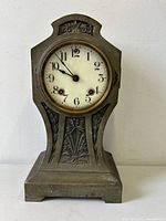 Front view of the Gothic antique metal mantel clock showing the circular clock face and decorative metal body.