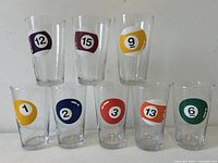 Front view showing all eight vintage billiard ball highball beverage glasses arranged in two rows with distinct billiard ball numbers and colors.