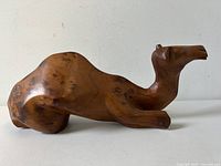 Side view of the carved wooden dromedary camel sculpture showing smooth polished olive wood surface with natural grain.