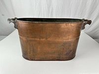 Front view showing oval copper log holder, riveted seams, wooden handles