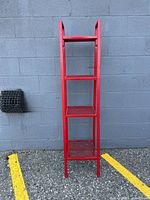 Front view of entire red metal shelf showing four tiers