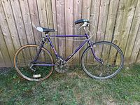 Full left side of purple CCM Esprit bicycle against wooden fence