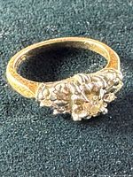 Top view of floral cluster ring showing central and surrounding stones on textured band.