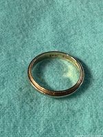 Top-down view of the polished gold band showing the continuous bridal knot motif