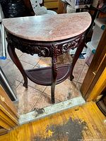 Full view of the half-moon red marble-topped hall table with carved wooden legs and lower shelf.