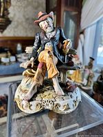 Front view of the Capodimonte Style porcelain figurine of a hobo sitting on a bench, showing detailed craftsmanship and hand-painted features.