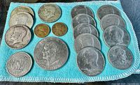 Top-down photo showing all 18 silver coins laid out on blue cloth, various types including half dollars and smaller denominations.