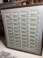 Full view of framed uncut sheet leaning against fireplace