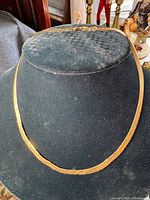 Front view of gold chain necklace draped on black velvet display bust
