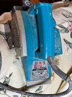 Side view of Makita Power Planer showing blue body, black handle, metal base, and power cord.