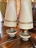Pair of mid-century modern ceramic textured lamps with tall fabric shades shown from the front and side.