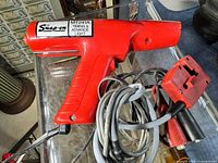 Red Snap-On MT241A Timing & Advance Light handheld tool with attached wires and connectors on glass table.