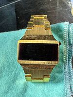 Front view showing red LED display and goldtone case and bracelet