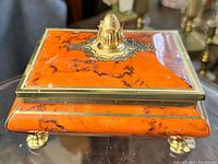 Top and side view showing orange marbled design and brass/gold ornate finial and trim.