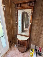 Full view of the vintage wooden coat rack with etched glass mirror and marble top shelf, showing the entire piece from top to bottom.