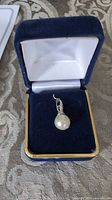 Pendant in open jewelry box showing pearl and bail