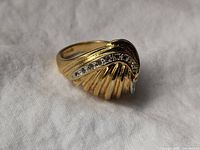 Ring side view showing sculpted gold plated design with small clear stones