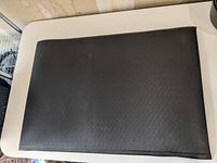 Black anti-fatigue mat laid flat showing entire top surface.